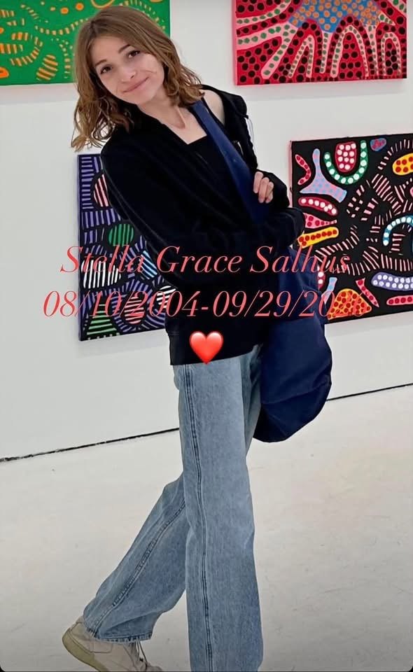 Stella Grace Salhus smiling in an art gallery, standing in front of colorful dotted paintings